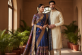 a women and man standing nearly ,women wear a saree while man wear a kurta pajama 